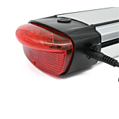El cargador de la batería compatible con Gazelle Innergy Gold está enchufado en el lateral de la batería. La luz trasera es claramente visible.