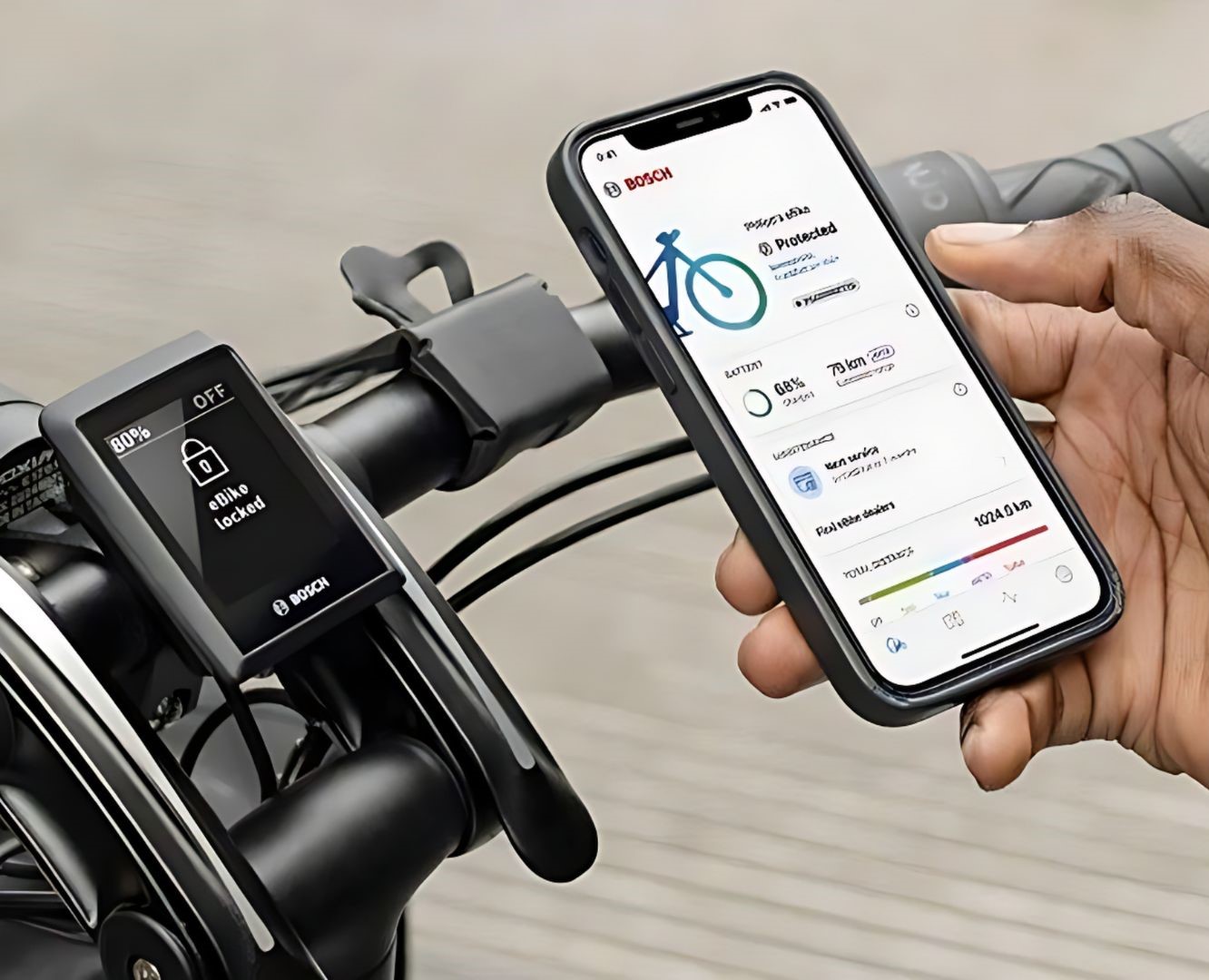 Imagen de un teléfono mostrando la aplicación Bosch E-bike Flow. Con una bicicleta eléctrica con soporte para teléfono al fondo.
